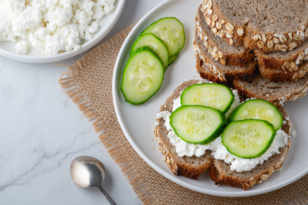 Slices of rye bread with cottage cheese and cucumbers on white background.. - Photo, Image