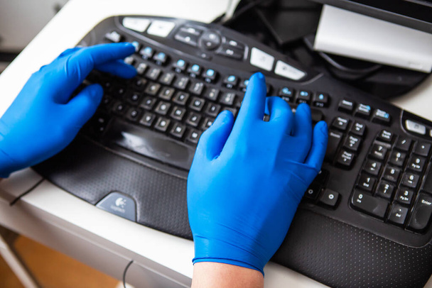 Ένας γιατρός με μπλε γάντια συλλέγει γρήγορα δεδομένα για έναν ασθενή. Η έννοια της υγειονομικής περίθαλψης και τη φροντίδα της υγείας σας - Φωτογραφία, εικόνα