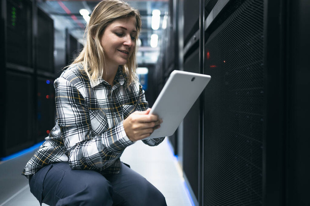 Tecnico di data center femminile che lavora all'interno della stanza del rack server - Foto, immagini