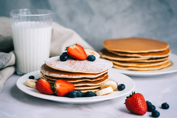 Tasty pancakes with strawberry, blueberry and banana in a white plate on the table. - Foto, Imagem