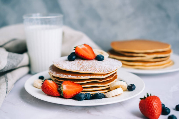 Tasty pancakes with strawberry, blueberry and banana in a white plate on the table. - Foto, imagen