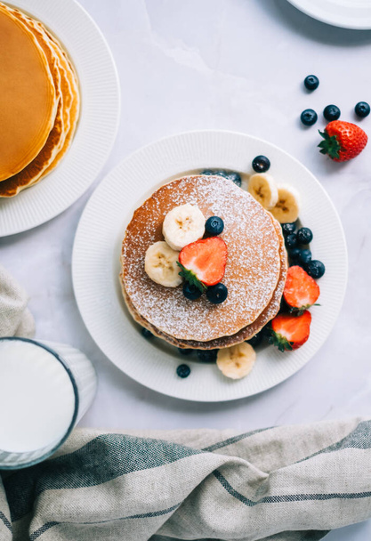 Tasty pancakes with strawberry, blueberry and banana in a white plate on the table. - Foto, Bild