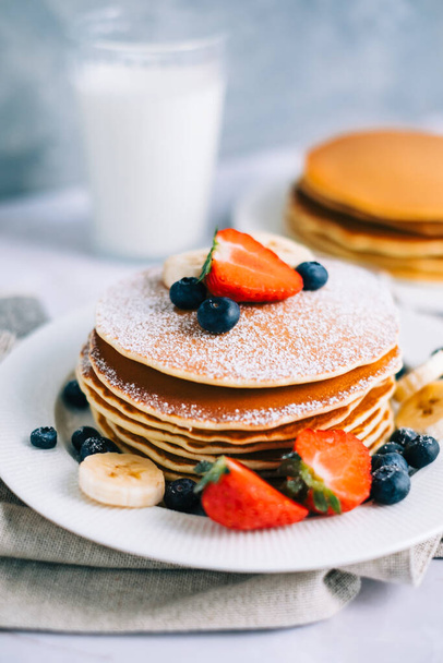 Tasty pancakes with strawberry, blueberry and banana in a white plate on the table. - Foto, imagen