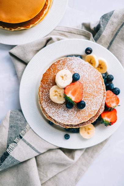 Tasty pancakes with strawberry, blueberry and banana in a white plate on the table. - Foto, Imagem