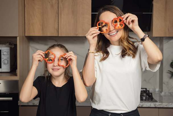 Glückliche Mutter und Tochter imitieren Gläser mit Paprika - Foto, Bild