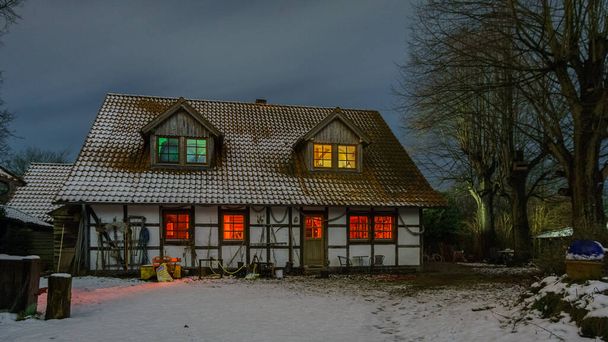 Casa de fazenda de madeira iluminada em uma noite de inverno nevada - Foto, Imagem