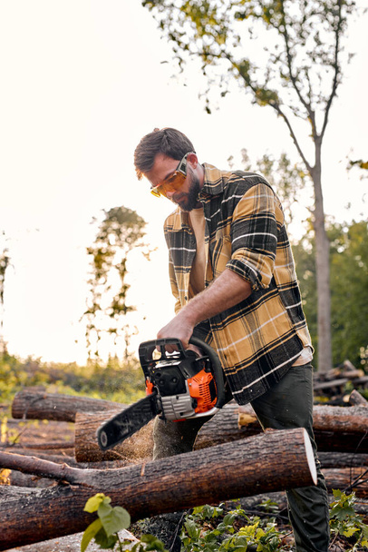 Wood man cuts a felled tree trunk with chainsaw. felled tree trunk is sawn by lumberjack - Photo, Image