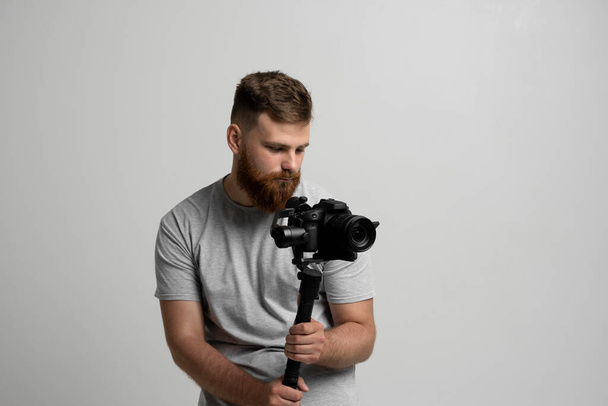 Professional bearded videographer holding camera which set on 3-axis gimbal. Videographer using steadicam. Pro equipment helps to make high quality video without shaking. - Foto, immagini