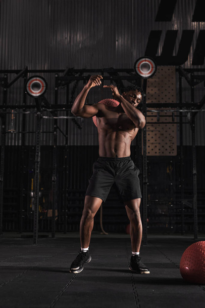 Fitness crossfit man holding medicine ball, workout in indoor crossfit gym. - Фото, зображення