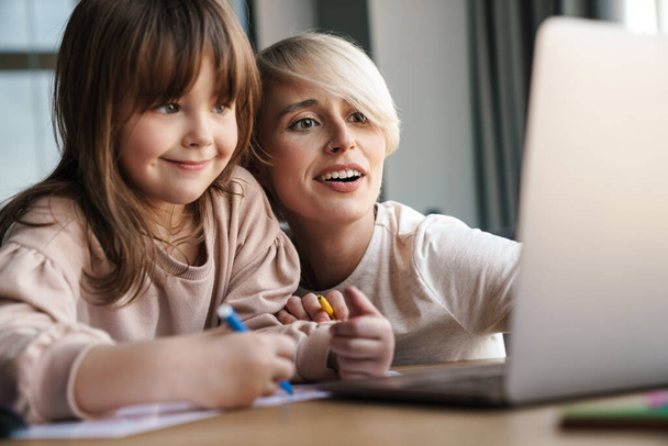 Mother helping her daughter with school homework, using laptop computer, study during quarantine - Φωτογραφία, εικόνα