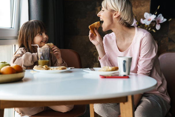 Happy young mother and her little daughter having breakfast - Valokuva, kuva