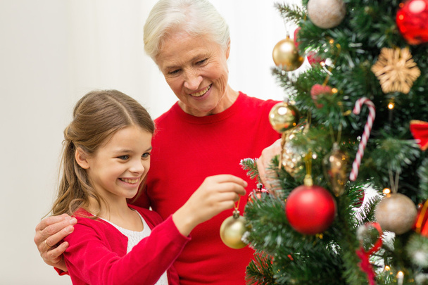 smiling family decorating christmas tree at home - Фото, зображення