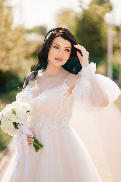 brunette bride in a dress with a bouquet of flowers outdoors  - Zdjęcie, obraz