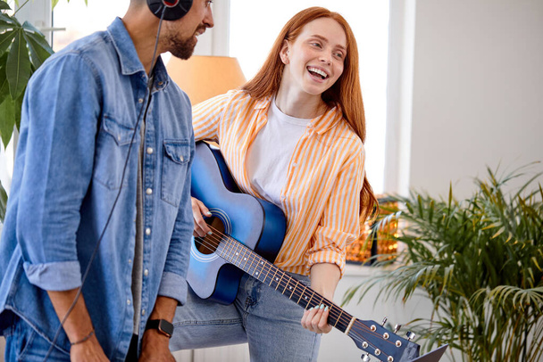 young woman and man playing guitar. Concept of home learning playing guitar - Фото, изображение