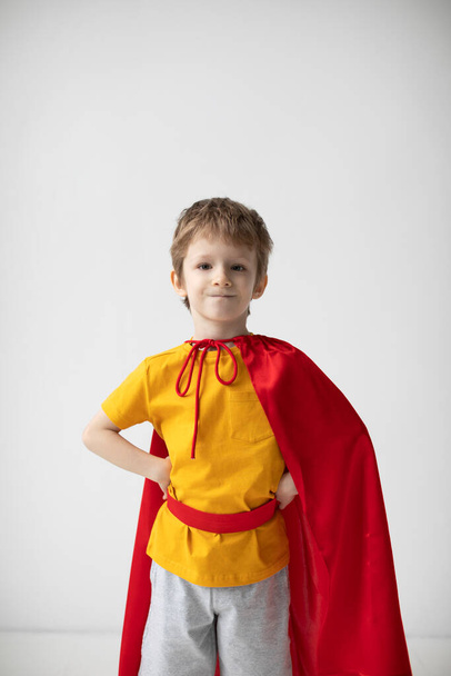 Little boy dressed like superhero standing alongside the white wall, having fun at home. - Foto, Imagem