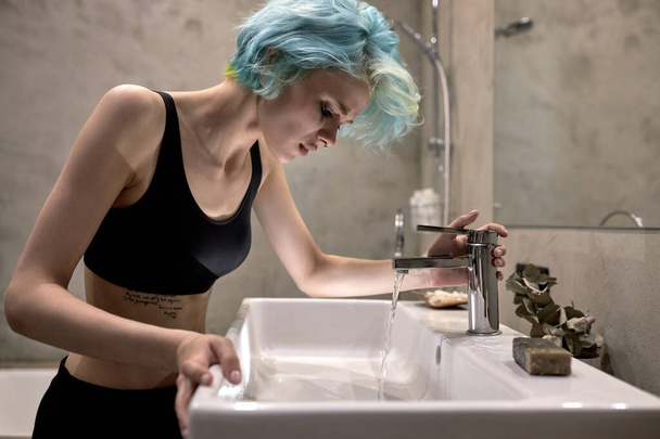 Young sad woman with smeared makeup is crying in bathroom. Concept of depression - Foto, Imagem