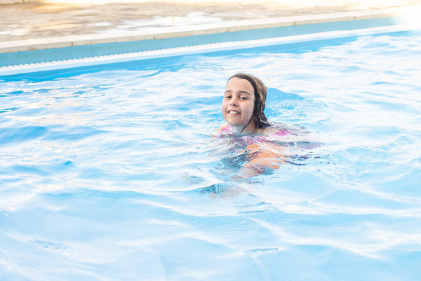 щаслива маленька дівчинка розважається в басейні в купальнику
. - Фото, зображення