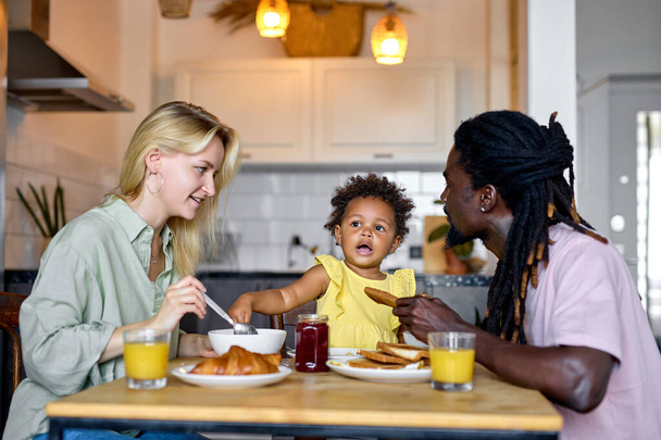 Cute family having breakfast together, enjoy meal at home in kitchen, in the morning - Photo, Image