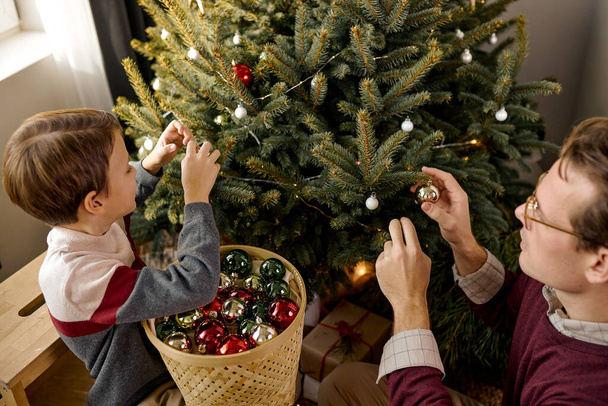 cute loving young caucasian father and little son have fun decorate Christmas tree together - Fotoğraf, Görsel