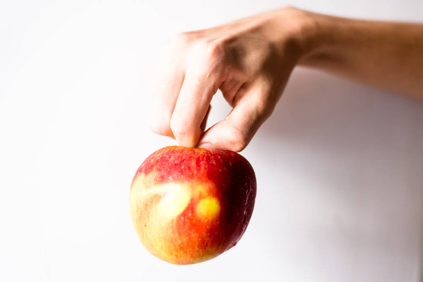 A hand holding an apple against white background. Salvador, Bahia, Brazil. - Foto, afbeelding