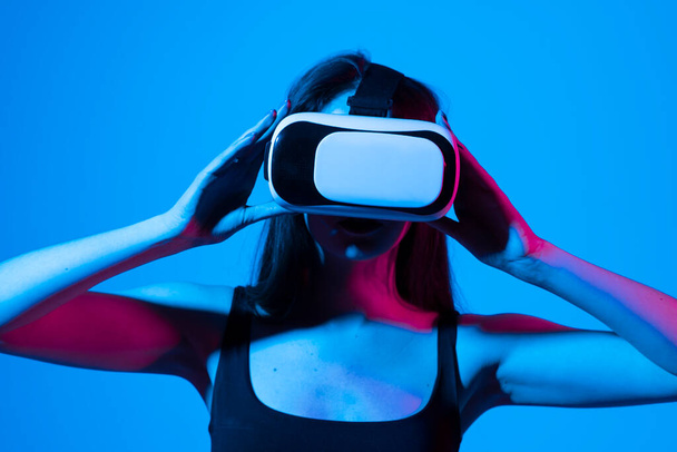 Brunette woman in vr glasses, watching 360 degree video with virtual reality headset illuminated by neon lights. - Foto, Imagem