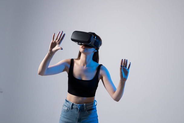 Young woman wearing VR goggles and interacts with cyberspace using swipe and stretching gestures. - Foto, afbeelding
