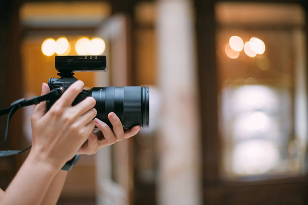 Egy közelkép egy profi kameráról női kezekben. Női fotós dolgozik forgatás, fókuszálás, keres egy kártyát, fotózás - Fotó, kép