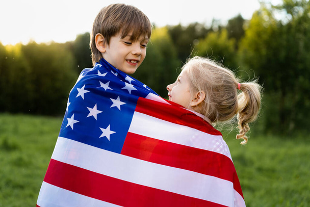 Amerikan bayrağına sarılmış kardeşlerim, Amerika 'nın Bağımsızlık Günü' nde mutlu çocuklar. - Fotoğraf, Görsel