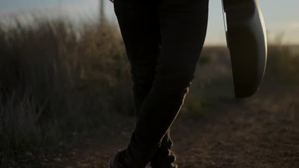 Attraktiver bärtiger kaukasischer Mann mit Gitarre im Stehen und Blick in die Kamera, nachdem er das Telefonat beendet hat, beleuchtet mit Sonnenuntergang - Filmmaterial, Video