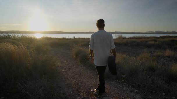 Der Mann mit der Gitarre dreht sich im Kreis gegen den schönen Sonnenuntergang - Filmmaterial, Video