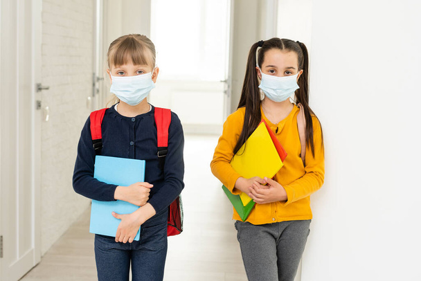 Dva žáci v ochranných maskách s batohy. den ve škole koncept - Fotografie, Obrázek