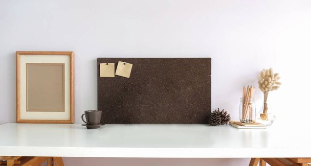 Cadre photo en bois, tasse à café et planche avec des notes collantes sur la table blanche. - Photo, image