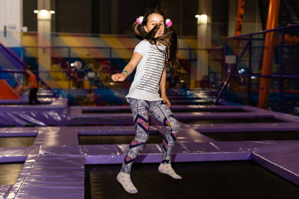Pieni lapsi hyppii trampoliinilla leikkikentällä. Aktiivinen lapsi tyttö hauskaa urheilukeskuksessa
. - Valokuva, kuva