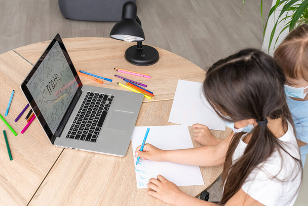 two little child girl studying online and working on laptop in wearing face mask - Foto, Bild