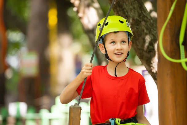 Lindo chico de escuela disfrutando de un día soleado en un parque de actividades de aventura de escalada - Foto, Imagen
