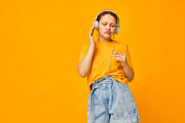 beautiful woman listening to music on headphones Youth style yellow background unaltered - Fotoğraf, Görsel