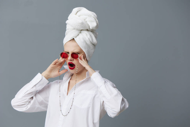 ファッショナブルな女性赤サングラス化粧品でタオル頭の上グレーの背景 - 写真・画像