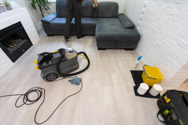 Collection of cleaning products and tools in living room, sofa cleaning products. - Foto, Bild