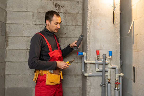 Bau-, Berufs- und Personenkonzept - Bau- oder Klempner arbeiten mit Wasserleitungen im Heizungsraum - Foto, Bild