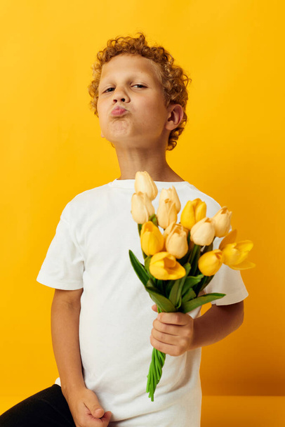 Photo portrait curly little boy with a bouquet of yellow flowers isolated background unaltered - Foto, imagen