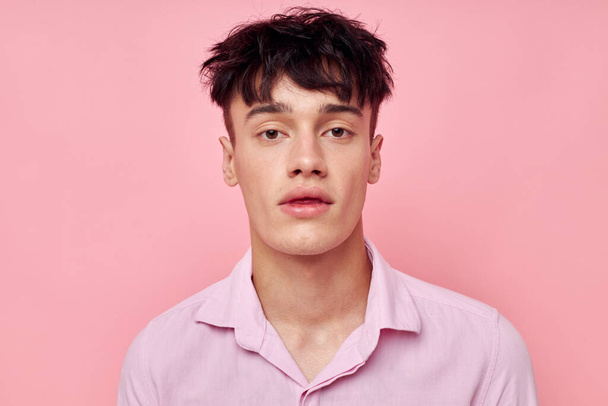 A young man in a pink shirt gesturing with his hands pink background unaltered - Photo, Image