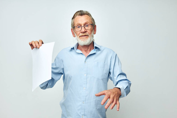 Portrait of happy senior man in a blue shirt and glasses a white sheet of paper cropped view - Photo, image