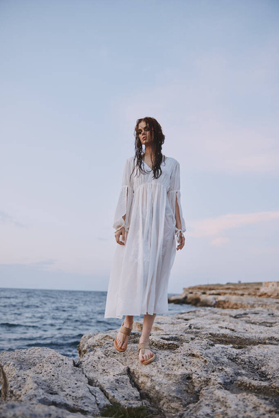 mujer bonita en túnica blanca paisaje océano rocas naturaleza inalterada - Foto, imagen
