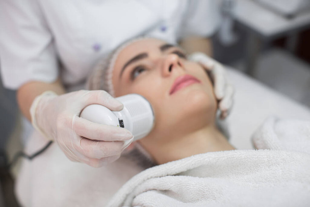 Cosmetology. Beautiful Woman Receiving Facial Skin Ultrasound Cavitation. Closeup Of Female Face Receiving Anti-Aging Cosmetics Using Ultrasound Cavitation Machine. Body Care. - Foto, Imagem
