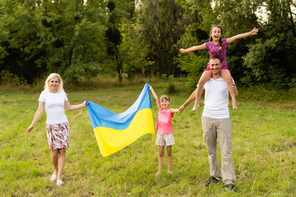 Ουκρανοί Ημέρα της Ανεξαρτησίας. Ημέρα Συντάγματος. οικογένεια με τη σημαία της Ουκρανίας στο πεδίο. 24 Αυγούστου. Πατριωτικές διακοπές. - Φωτογραφία, εικόνα