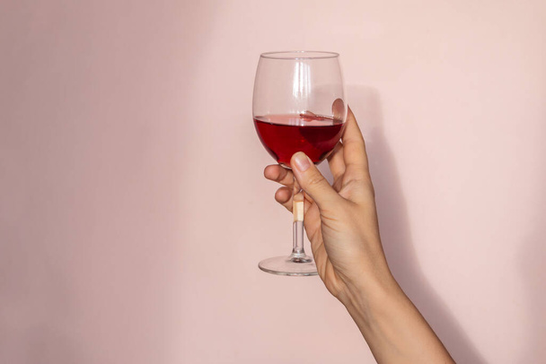 Kadın elinde kırmızı şarap kadehi, güneş ışığı ve soyut gölge tutuyor. Retro biçimli fotoğrafçılık  - Fotoğraf, Görsel
