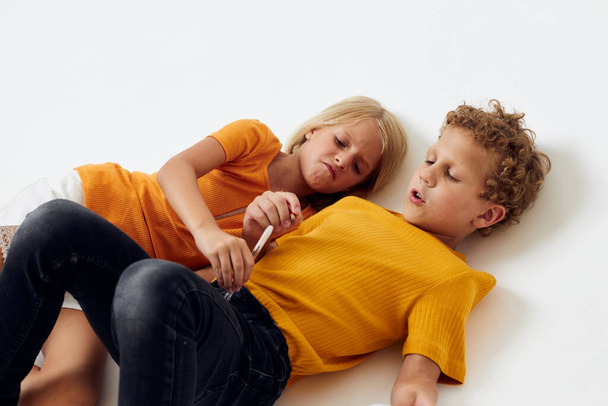 Cute stylish kids lie on the floor with notepads and pencils childhood lifestyle unaltered - Foto, imagen