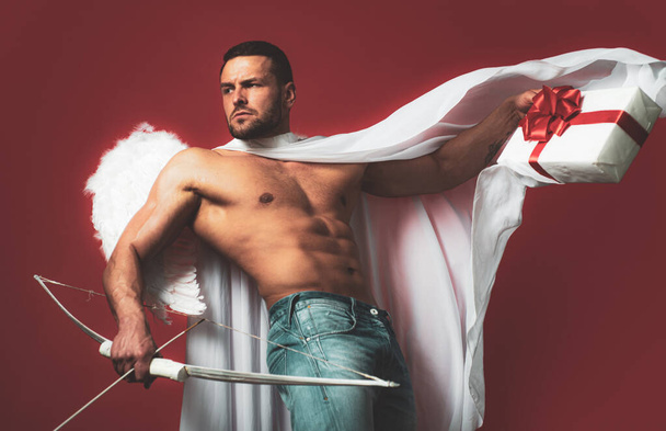 Sexy man on valentines day. Handsome angel man with angel wings. Great present for girlfriend. Charms of love. Valentine gift. Sexy guy on red background. Cupid shoot with bow and arrows - 写真・画像
