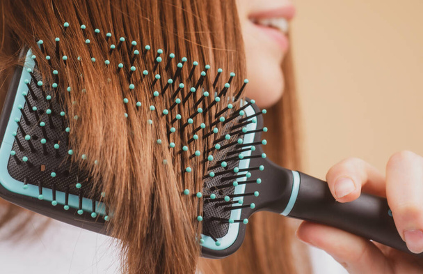 Close up smiling woman brushing hair with comb. Beautiful girl with long hair hairbrush. - Φωτογραφία, εικόνα