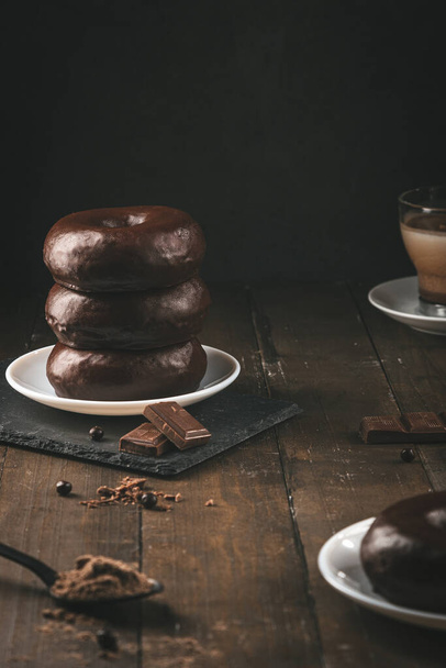 Stack of chocolate donuts on dark background. Vertical format. - Photo, Image
